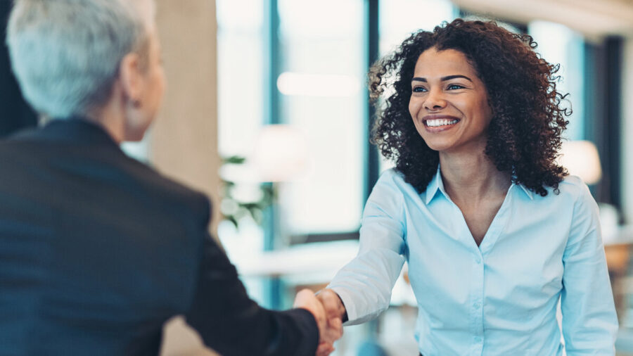Smiling Businesswoman Greeting A Colleague with a handshake