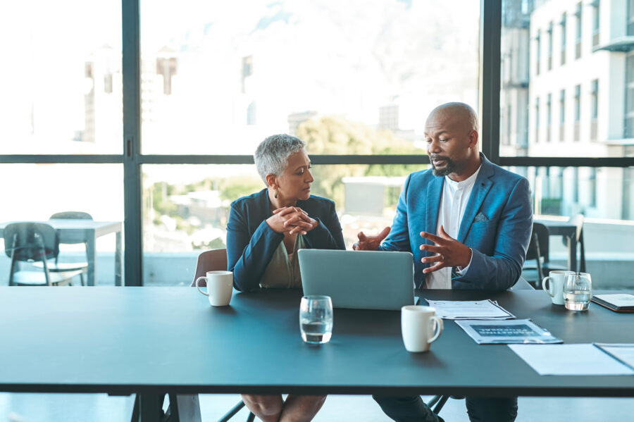 Business, Presentation And Man On A Laptop In A Corporate Conference Or Office Collaboration With A Woman At Work. Businessman, Manager Or Coach For Marketing, Strategy And Sales Working With Ceo.