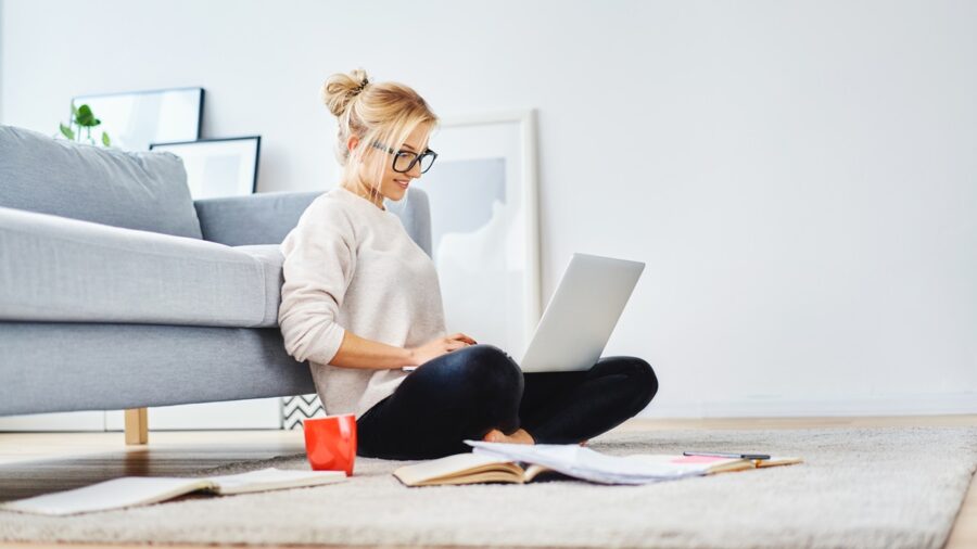 Female worker Sitting On Floor Of Her Apartment With Laptop