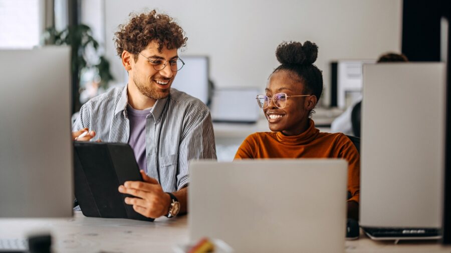 Two Young Colleagues Working Together At Modern Office